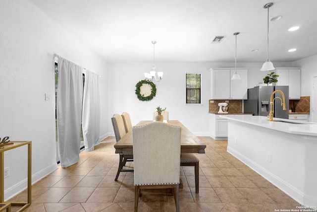 dining space featuring light tile patterned floors, a notable chandelier, and sink