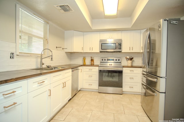 kitchen featuring butcher block counters, sink, tasteful backsplash, white cabinetry, and stainless steel appliances