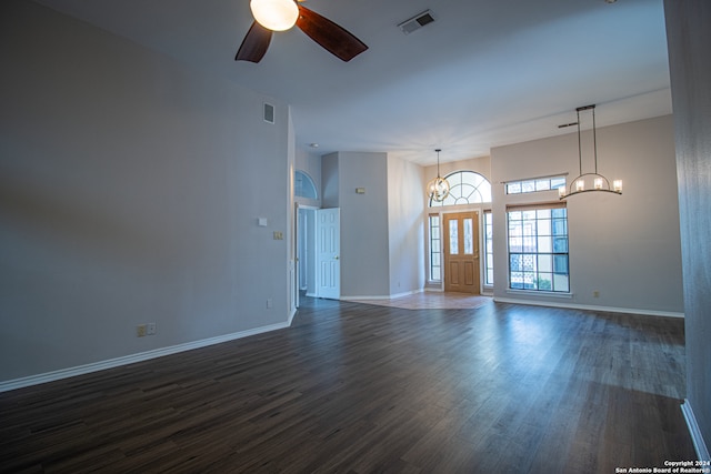 empty room with ceiling fan with notable chandelier and dark hardwood / wood-style floors