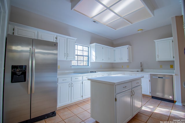 kitchen featuring a center island, sink, light tile patterned flooring, white cabinetry, and stainless steel appliances