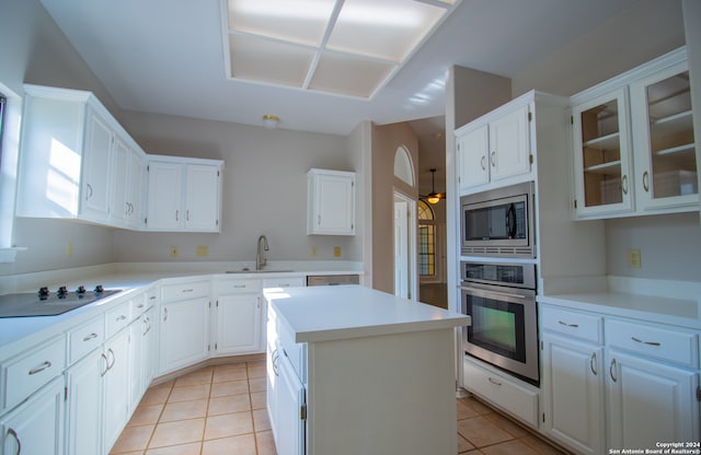 kitchen with white cabinetry, sink, light tile patterned flooring, a kitchen island, and appliances with stainless steel finishes