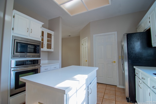 kitchen with light tile patterned floors, a center island, stainless steel appliances, and white cabinetry