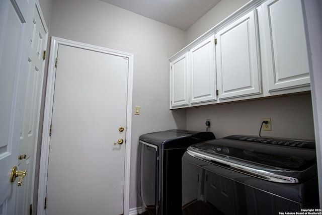 clothes washing area featuring cabinets, a textured ceiling, and washing machine and clothes dryer