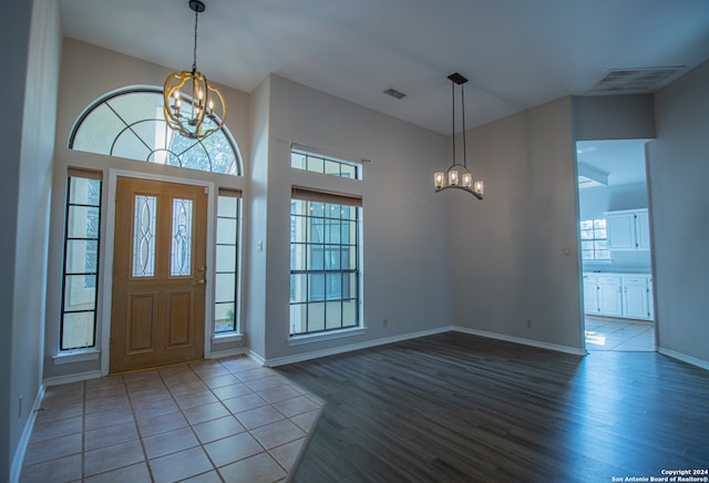 entrance foyer with wood-type flooring, a wealth of natural light, and a chandelier