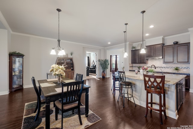 dining room featuring sink, a notable chandelier, dark hardwood / wood-style flooring, and crown molding