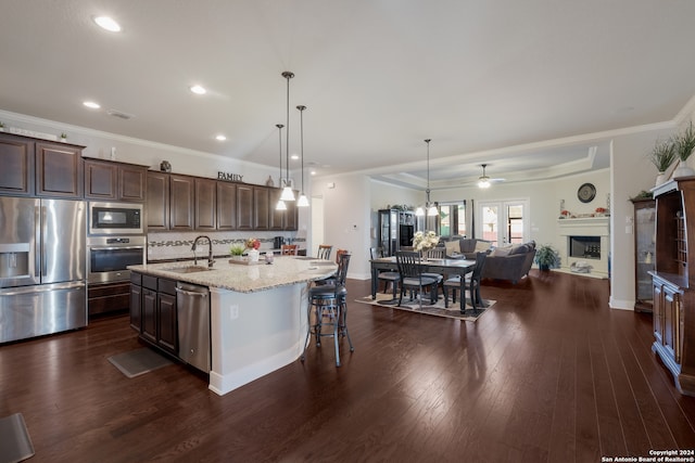 kitchen with a kitchen island with sink, dark wood-type flooring, sink, appliances with stainless steel finishes, and dark brown cabinets