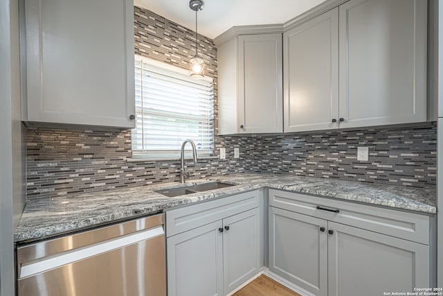 kitchen featuring decorative backsplash, light stone counters, stainless steel dishwasher, and sink