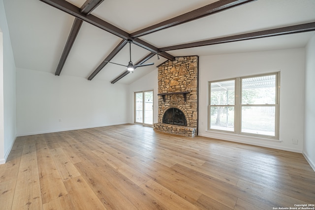 unfurnished living room with vaulted ceiling with beams, light wood-type flooring, a stone fireplace, and ceiling fan