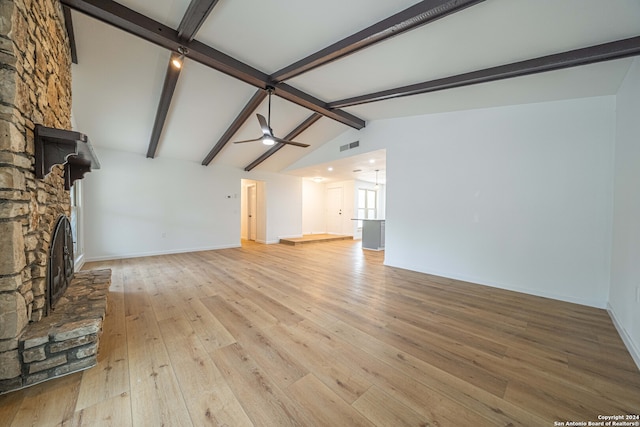 unfurnished living room featuring lofted ceiling with beams, ceiling fan, a stone fireplace, and light hardwood / wood-style flooring