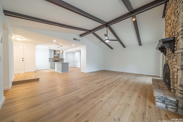 unfurnished living room featuring vaulted ceiling with beams, light hardwood / wood-style floors, a fireplace, and ceiling fan