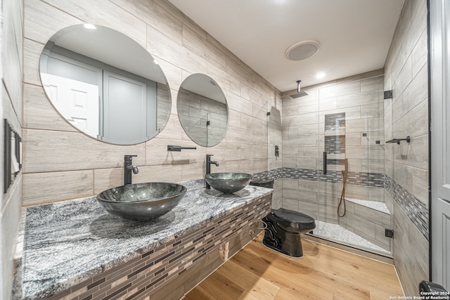 bathroom featuring a shower with door, wood-type flooring, sink, and tile walls