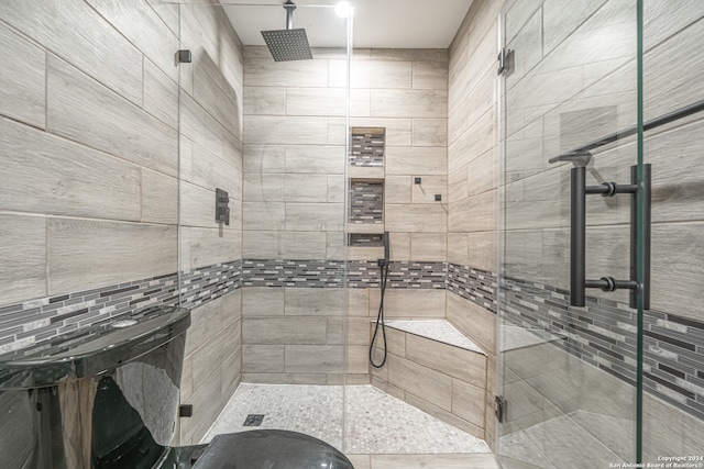 bathroom featuring decorative backsplash, a shower with shower door, and tile walls