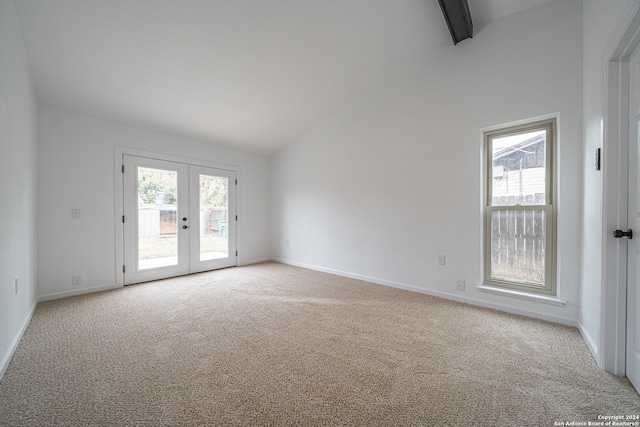 carpeted spare room featuring french doors and high vaulted ceiling