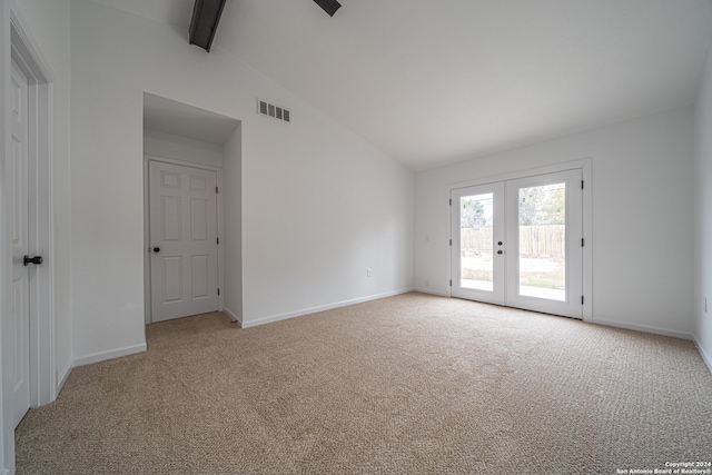 empty room featuring lofted ceiling with beams, light colored carpet, and french doors