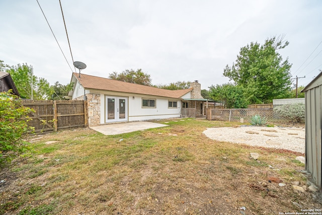 rear view of property featuring french doors, a patio, and a lawn