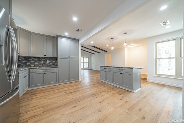 kitchen featuring gray cabinetry, stainless steel refrigerator with ice dispenser, and a wealth of natural light