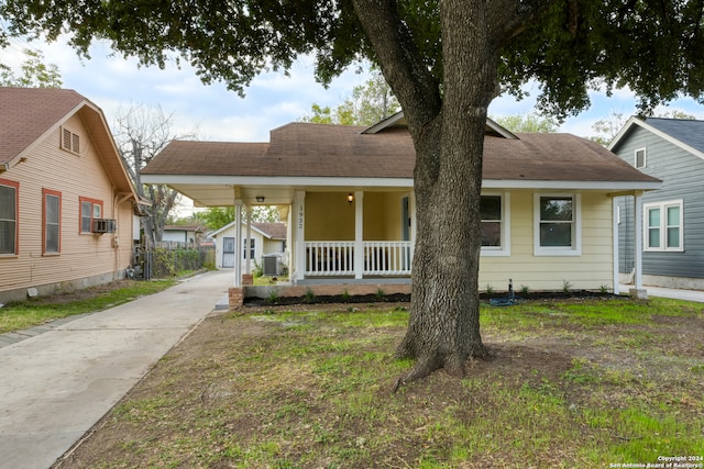 view of front facade with a front lawn, an outbuilding, cooling unit, and covered porch