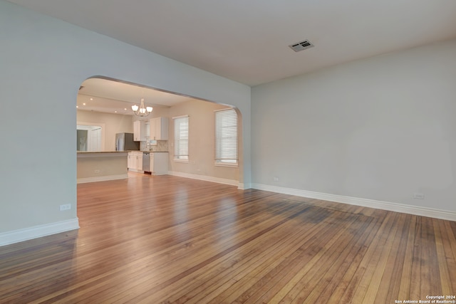 unfurnished living room with hardwood / wood-style flooring and a notable chandelier