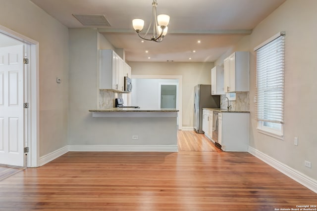 kitchen featuring light wood-type flooring, white cabinetry, appliances with stainless steel finishes, and tasteful backsplash