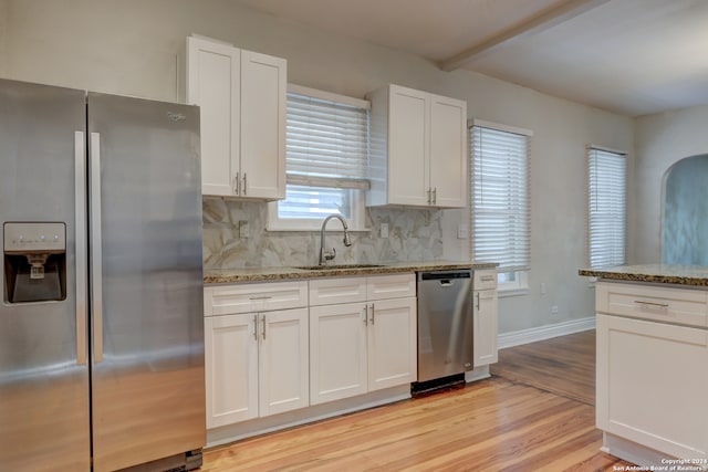 kitchen featuring white cabinetry, sink, light stone counters, light hardwood / wood-style flooring, and appliances with stainless steel finishes