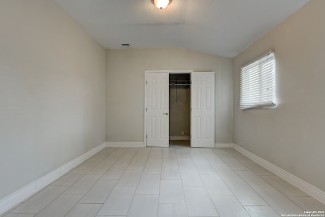 unfurnished bedroom with a closet, light tile patterned flooring, and lofted ceiling