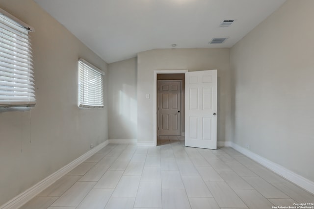 spare room featuring lofted ceiling and light tile patterned floors