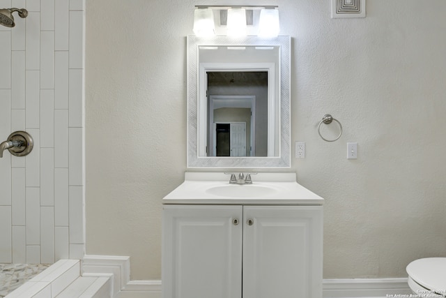 bathroom with vanity, toilet, and a tile shower