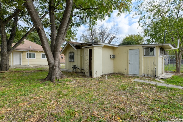 back of house with a yard and a wall mounted air conditioner