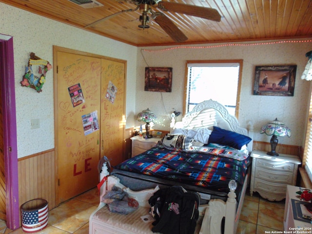 bedroom with ceiling fan, wooden walls, light tile patterned floors, and wood ceiling