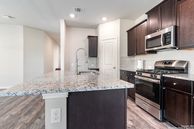 kitchen featuring a center island with sink, light hardwood / wood-style floors, sink, and appliances with stainless steel finishes