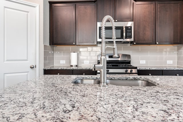 kitchen featuring dark brown cabinets, light stone countertops, and appliances with stainless steel finishes