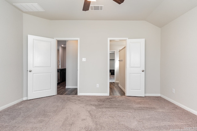 unfurnished bedroom featuring vaulted ceiling, a spacious closet, dark carpet, and ceiling fan