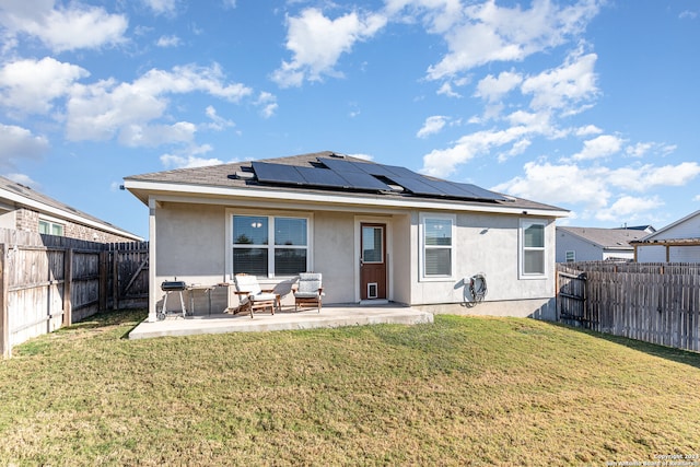 rear view of property with solar panels, a yard, and a patio