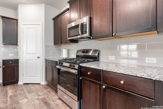 kitchen with backsplash, dark brown cabinetry, light wood-type flooring, and appliances with stainless steel finishes