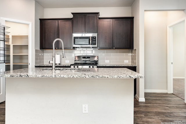 kitchen featuring decorative backsplash, a kitchen island with sink, and appliances with stainless steel finishes