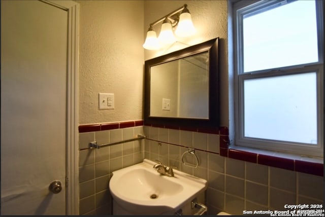 bathroom featuring sink and tile walls