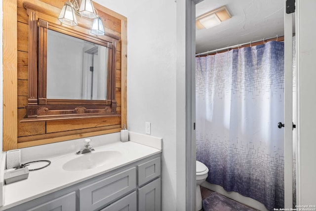 bathroom featuring curtained shower, vanity, and toilet