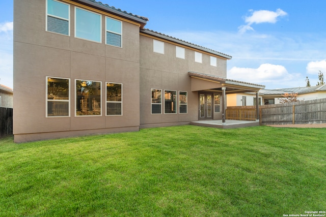 rear view of property featuring a lawn and a patio area