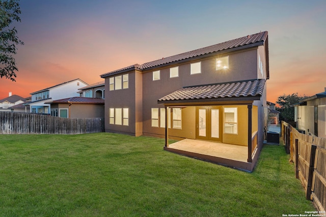 back house at dusk with a patio area and a yard