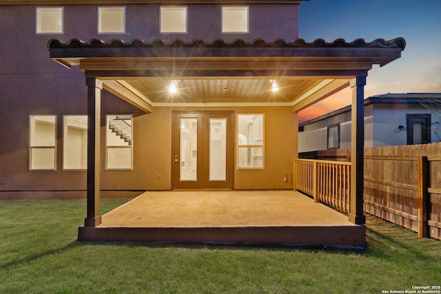 exterior entry at dusk with a yard and a patio area