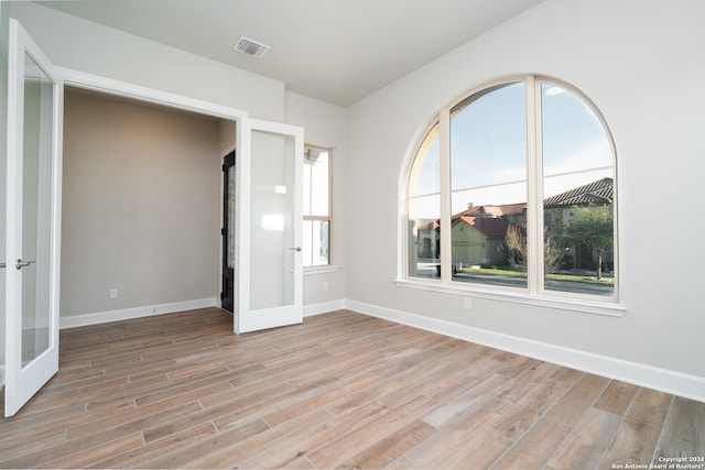 unfurnished room featuring french doors and light hardwood / wood-style flooring