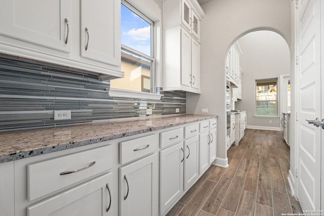 kitchen featuring white cabinets, light stone counters, tasteful backsplash, dark hardwood / wood-style flooring, and plenty of natural light