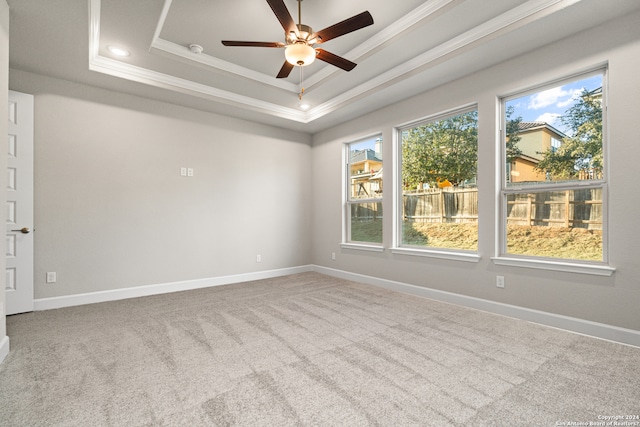 carpeted spare room with ceiling fan, a tray ceiling, and crown molding