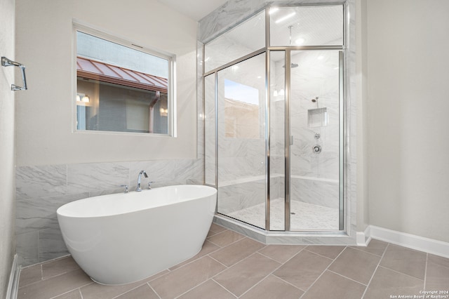 bathroom with independent shower and bath, tile patterned flooring, and tile walls