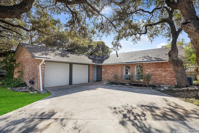 single story home with central AC unit and a garage