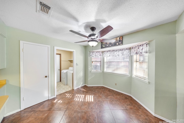 unfurnished dining area with washer and dryer, a textured ceiling, ceiling fan, and tile patterned flooring