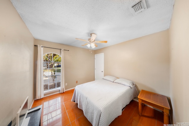 bedroom with tile patterned floors, ceiling fan, and a textured ceiling