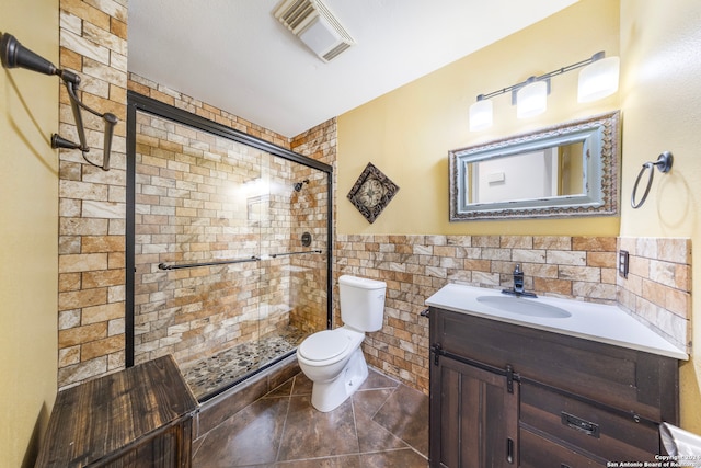 bathroom featuring tile patterned floors, an enclosed shower, vanity, tile walls, and toilet