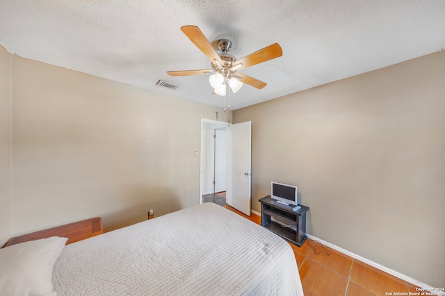 bedroom with a textured ceiling, tile patterned floors, and ceiling fan