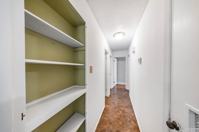 hall with tile patterned flooring and a textured ceiling